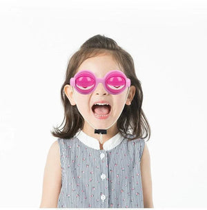 Child wearing pink eye-shaped funny glasses prank toy on white background