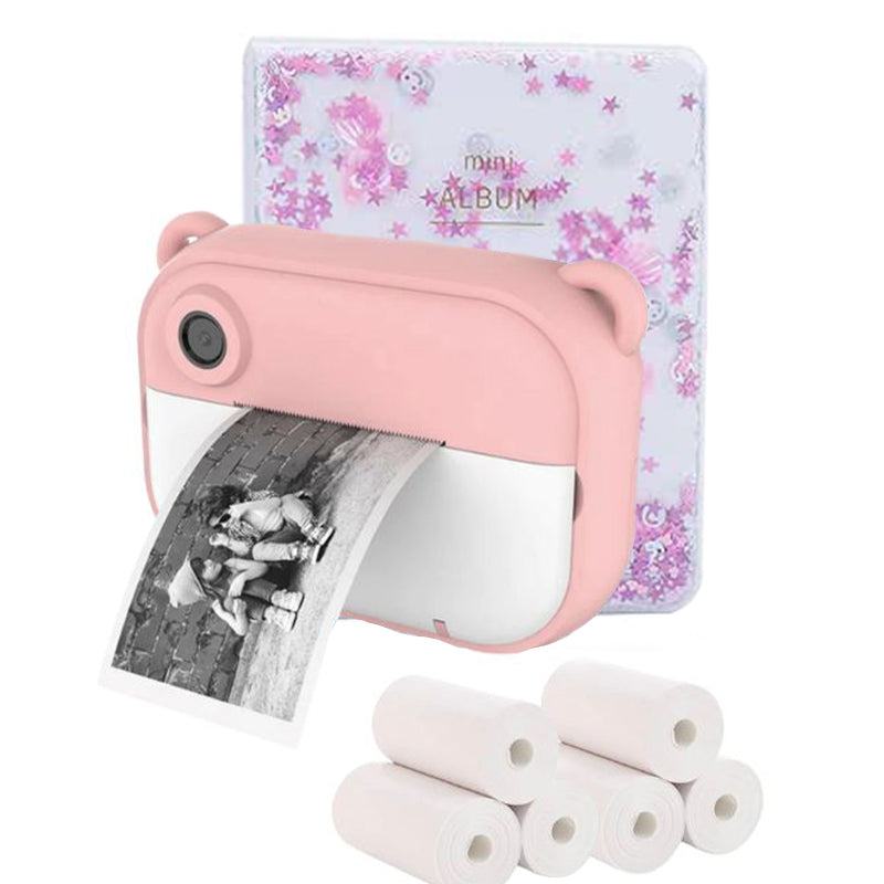 Pink kid instant print camera printing black and white photo with thermal paper rolls and mini photo album in background