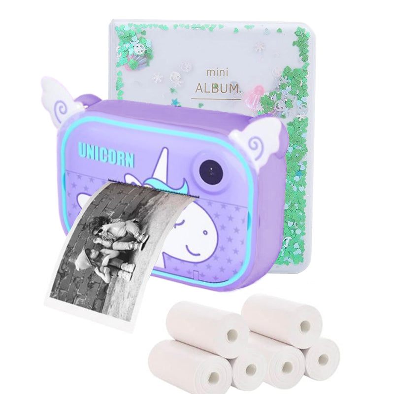 Purple kid instant print camera with unicorn design printing a black and white photo, mini photo album, and thermal paper rolls bundle